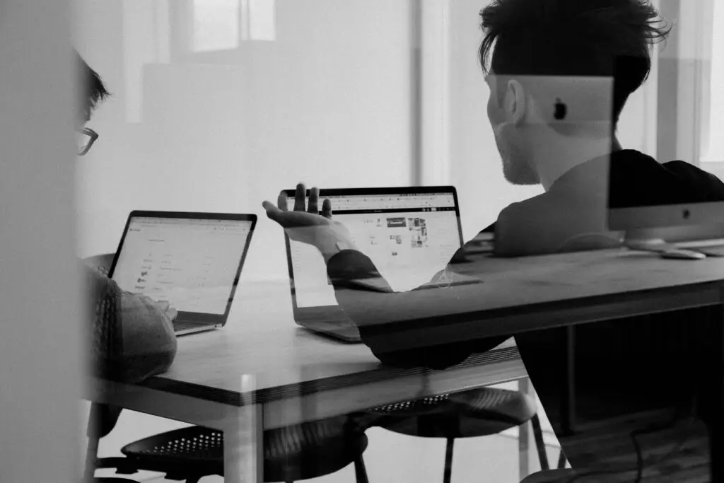 Kollegor diskuterar över deras laptops