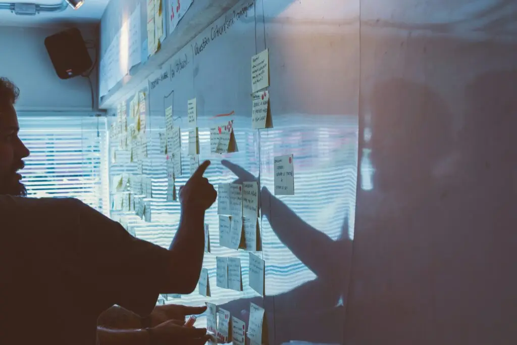 Man som pekar på tavla med post-it lappar
